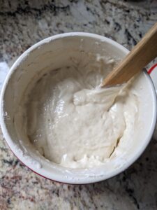 Fed sourdough starter in crock with mixing spoon